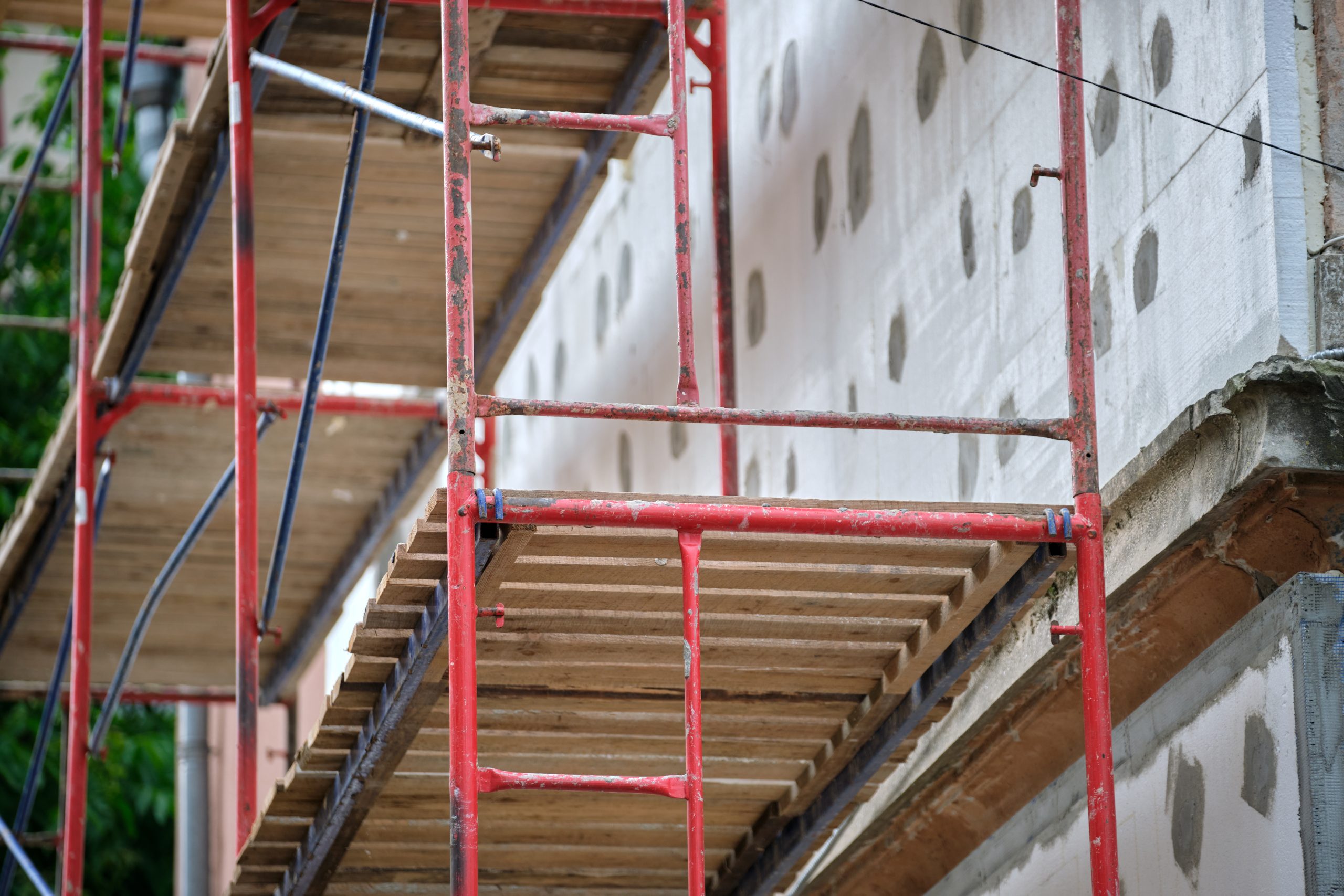 Building facade under renovation works with construction scaffolding frame. Wall insulation with styrofoam sheets for energy efficient home.